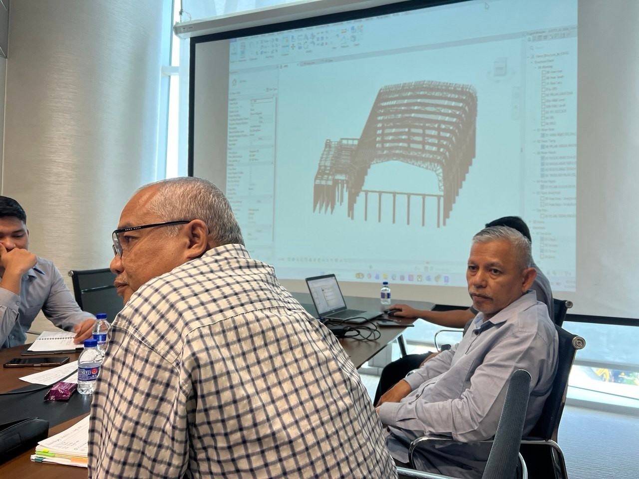 Technical discussion with a structural model presented on screen